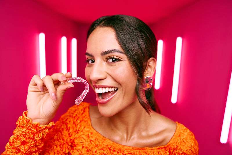 [CRO] Women - Brunette - Orange - Long sleeve - Aligners - Looking left - Pink - Light - Background - Desktop